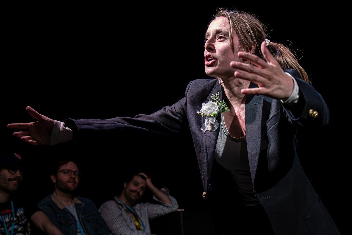 Grace Fennell leaning into the audience with one arm outstretched, front row visible.